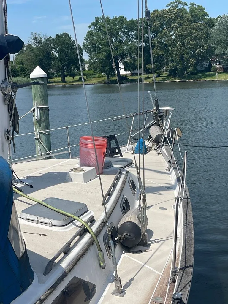 Slide: The Image of A 1985 Catalina Morgan 43 sailboat docked on calm waters, with trees in the background. - 3