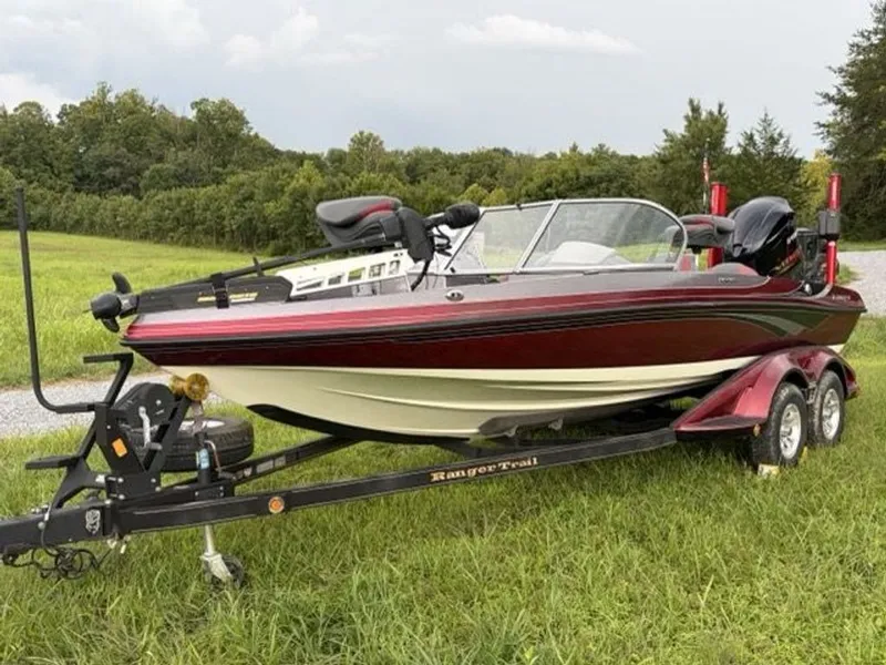The Image of A red Ranger 212LS Reata boat on a trailer sits on a grassy field. - 0