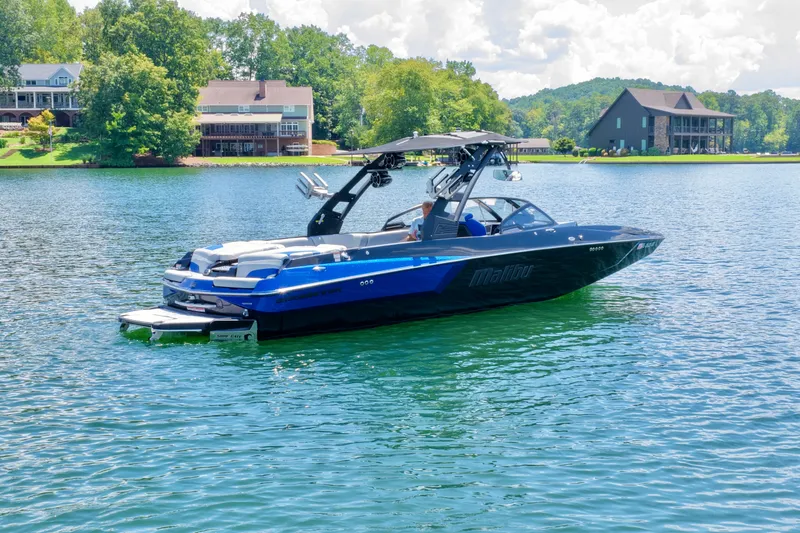 Slide: The Image of 2020 Malibu Wakesetter 24 MXZ boat on a serene lake with houses in the background. - 4