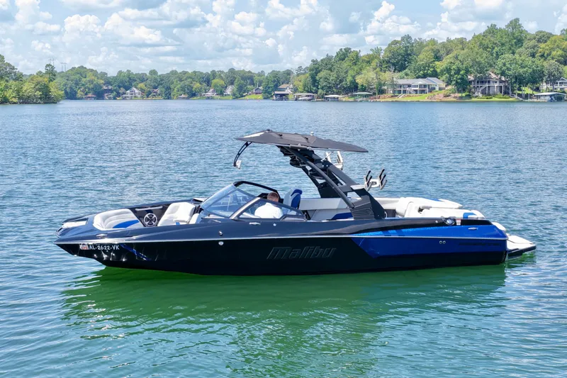 Slide: The Image of 2020 Malibu Wakesetter 24 MXZ boat on a serene lake with lush green shoreline. - 7