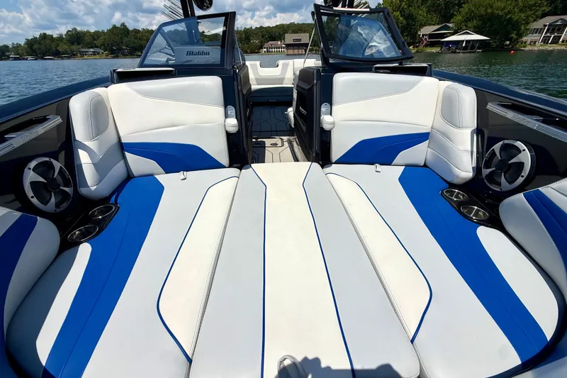 Slide: The Image of 2020 Malibu Wakesetter 24 MXZ interior with blue and white seating on a lake. - 28