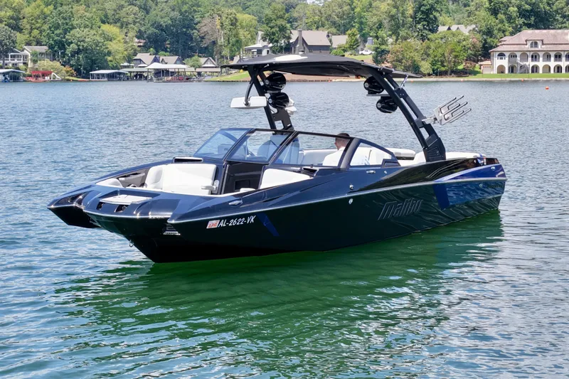 Slide: The Image of 2020 Malibu Wakesetter 24 MXZ boat on a serene lake with lush greenery. - 9
