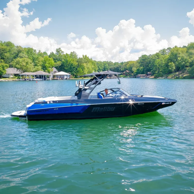The Image of A 2020 Malibu Wakesetter 24 MXZ cruising on a calm lake with wooded shores. - 0