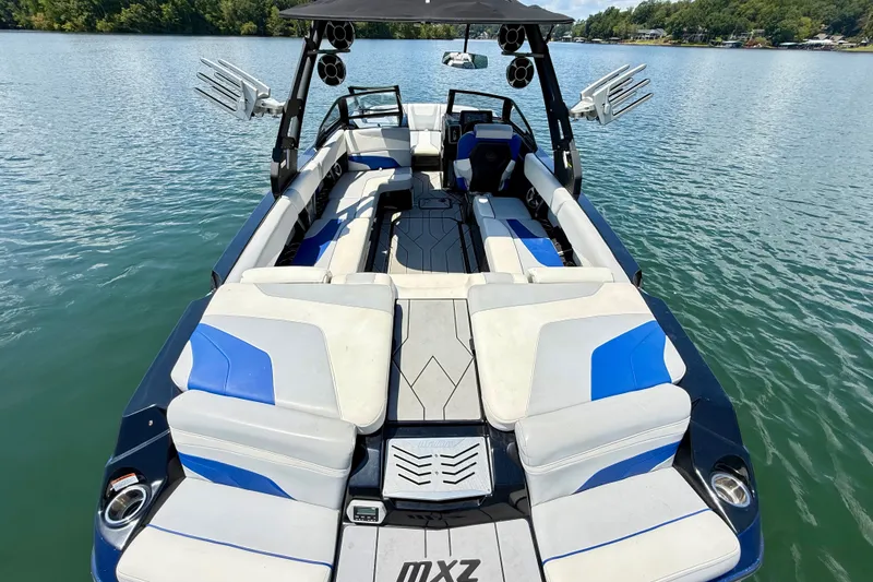 Slide: The Image of 2020 Malibu Wakesetter 24 MXZ boat interior with blue and white seating on a lake. - 11