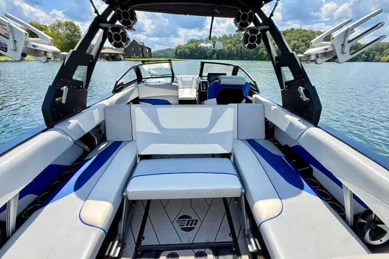Slide: The Image of 2020 Malibu Wakesetter 24 MXZ interior with blue and white seating on a lake. - 13