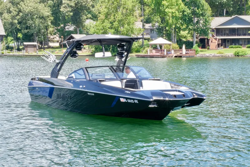 Slide: The Image of 2020 Malibu Wakesetter 24 MXZ boat on a serene lake near waterfront homes. - 10