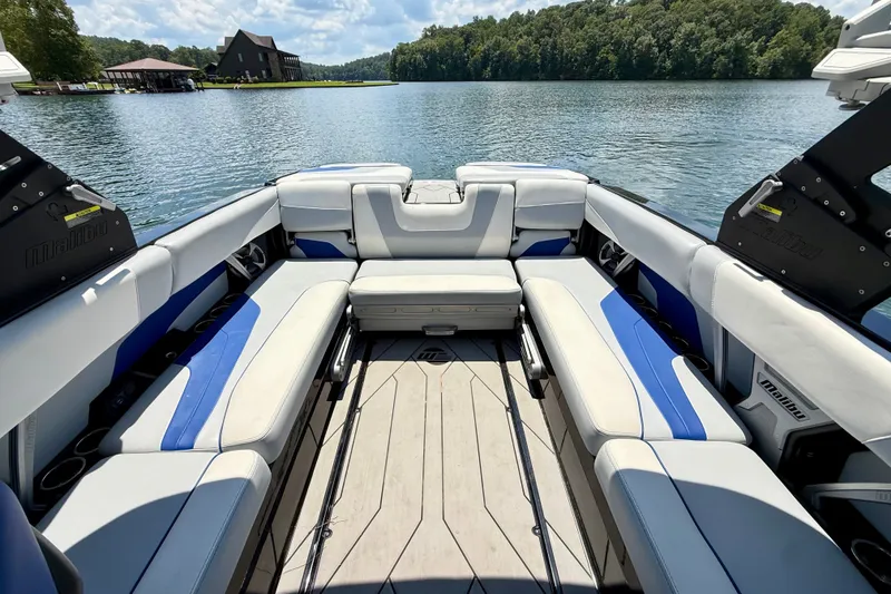 Slide: The Image of 2020 Malibu Wakesetter 24 MXZ interior with spacious seating on a serene lake. - 30