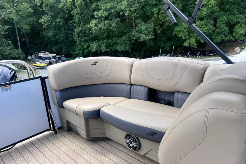 Slide: The Image of 2024 Starcraft SLS 3 boat interior with beige seating, surrounded by lush greenery. - 9