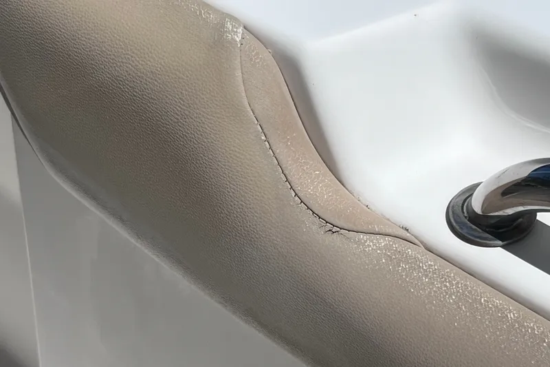 Slide: The Image of Cracked upholstery on a 2016 Key West 203 FS boat seat, near a metal handle. - 40