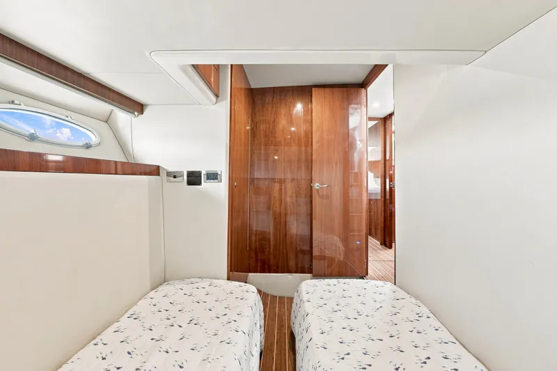 Slide: The Image of Interior of 2009 Riviera 4700 Sport Yacht with twin beds and wooden accents. - 22