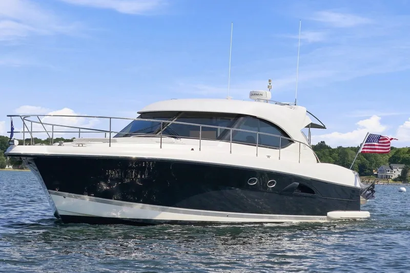 Slide: The Image of The 2009 Riviera 4700 Sport Yacht is cruising on calm waters. It features a sleek, modern design. - 2