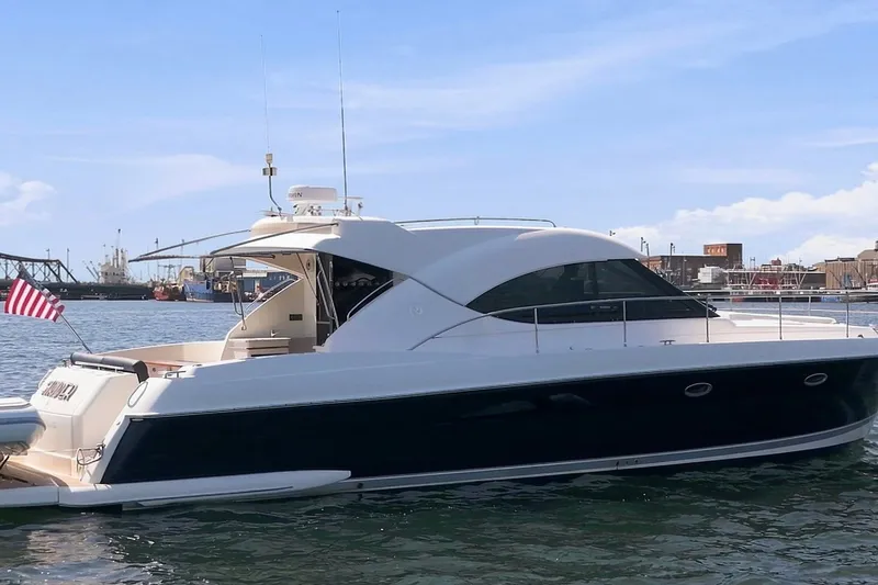 Slide: The Image of 2009 Riviera 4700 Sport Yacht in harbor, sleek design, American flag, clear sky. - 5