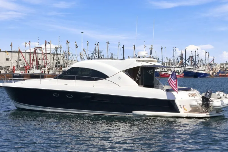 Slide: The Image of 2009 Riviera 4700 Sport Yacht docked in a bustling marina, featuring sleek design and American flag. - 1