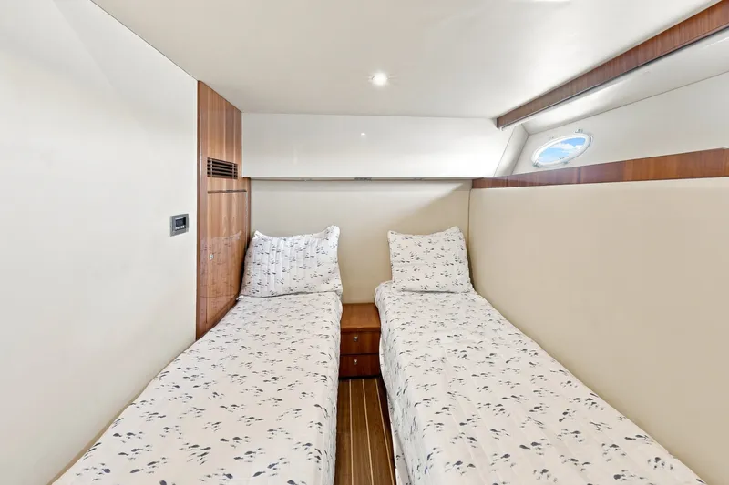 Slide: The Image of Interior cabin of 2009 Riviera 4700 Sport Yacht with twin beds and wooden accents. - 23