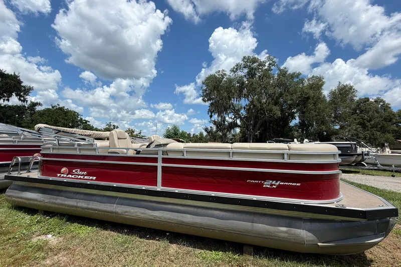 The Image of 2025 Sun Tracker Party Barge 24 DLX pontoon boat under a blue sky. - 0