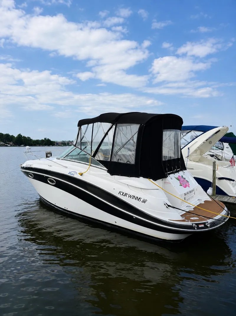 Slide: The Image of A 2006 Four Winns 278 Vista with a black canopy is docked in the water, surrounded by other boats. - 1