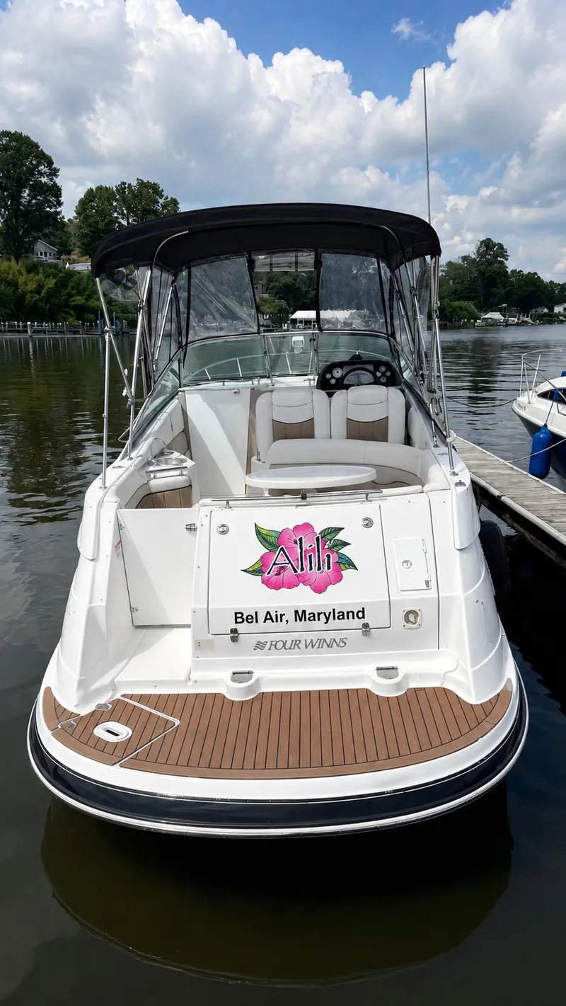 Slide: The Image of A 2006 Four Winns 278 Vista boat docked. It features an open cockpit and a black canopy. - 2