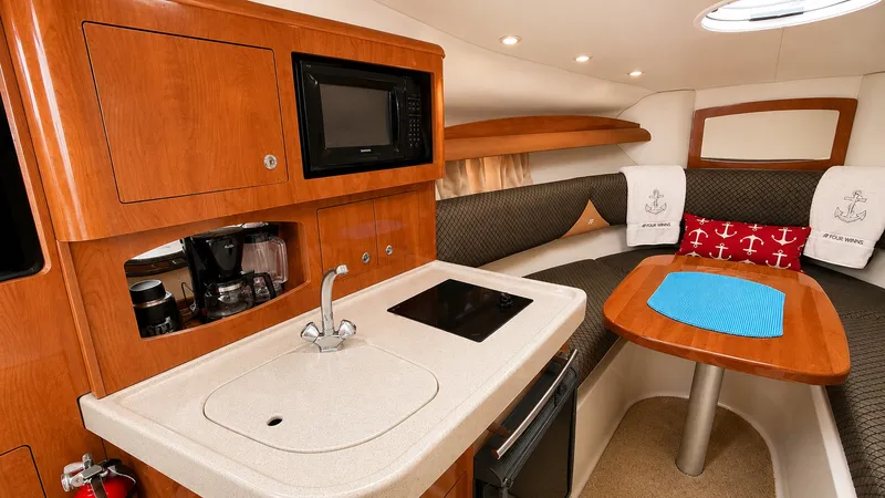 Slide: The Image of The cabin of a 2006 Four Winns 278 Vista with wood cabinetry, sink, microwave, and seating area. - 7