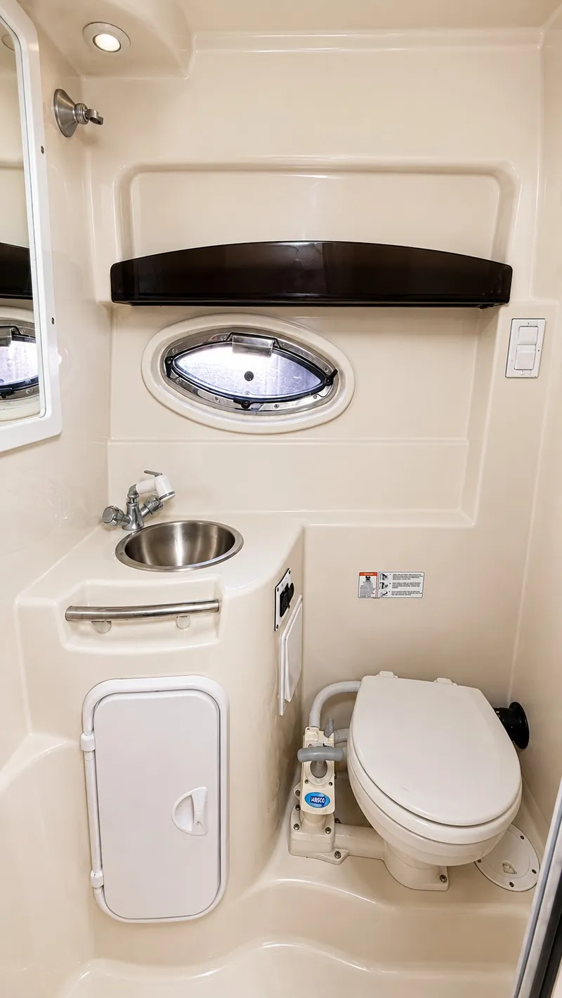 Slide: The Image of The image shows a compact boat bathroom with a sink, toilet, and porthole. - 12