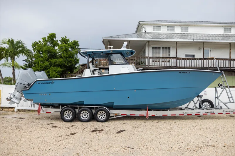 Slide: The Image of 2025 Freeman 35 boat on trailer, blue hull, dual engines, parked near house. - 53