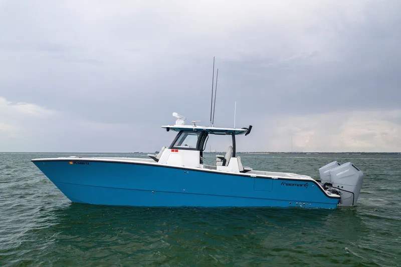 The Image of 2025 Freeman 35 boat on open water, featuring a sleek blue design and twin Mercury engines. - 1