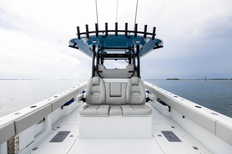 Slide: The Image of 2025 Freeman 35 boat interior with cushioned seating and rod holders on calm water. - 42