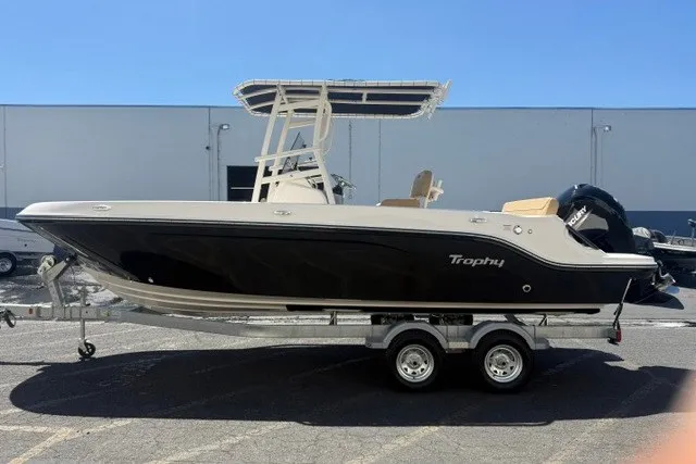 Slide: The Image of 2026 Bayliner Trophy T22CX boat on trailer, black hull, parked outdoors. - 20