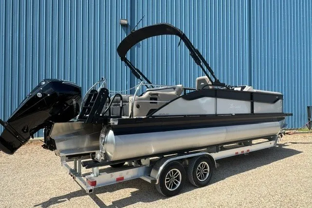 Slide: The Image of 2027 Barletta Aria 24UC pontoon boat on trailer, parked by blue building. - 3