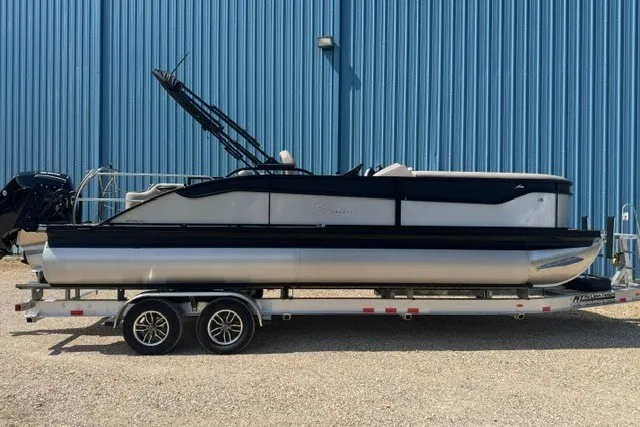 The Image of 2027 Barletta Aria 24UC pontoon boat on trailer, parked by blue building. - 0