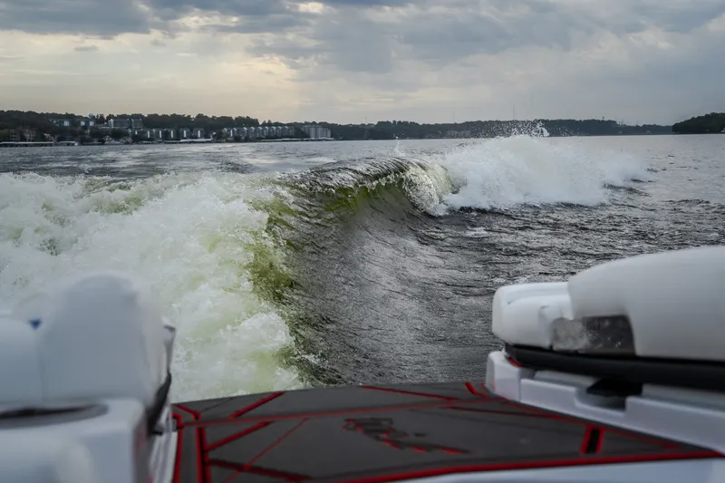 Slide: The Image of Wake surfing behind a 2027 Tige Ultré 25ZX boat on a cloudy day. - 14
