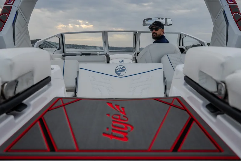 Slide: The Image of 2027 Tigé Ultré 25ZX boat interior with a person at the helm, under cloudy skies. - 52