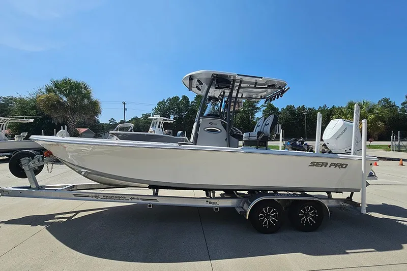 Slide: The Image of 2026 Sea Pro 250 Bay boat on trailer, parked outdoors under clear blue sky. - 7
