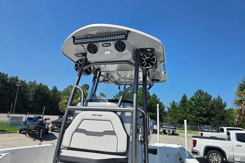 Slide: The Image of 2026 Sea Pro 250 Bay boat with T-top and speakers, parked outdoors under clear blue sky. - 22