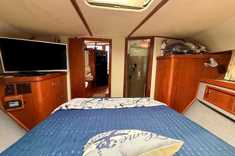 Slide: The Image of 1989 Tiara Yachts 3600 Convertible cabin interior with bed, TV, and wooden cabinetry. - 45