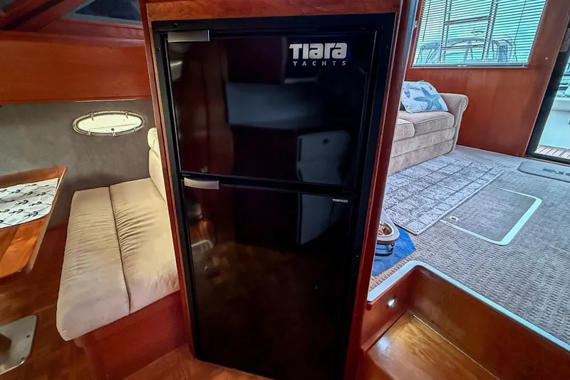 Slide: The Image of 1989 Tiara Yachts 3600 Convertible interior with fridge, seating, and carpeted floor. - 37