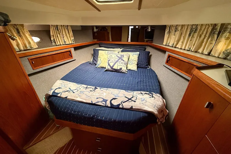 Slide: The Image of 1989 Tiara Yachts 3600 Convertible cabin with nautical-themed bedding and wood accents. - 43