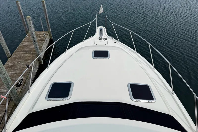 Slide: The Image of 1989 Tiara Yachts 3600 Convertible boat docked, view from bow over calm water. - 17