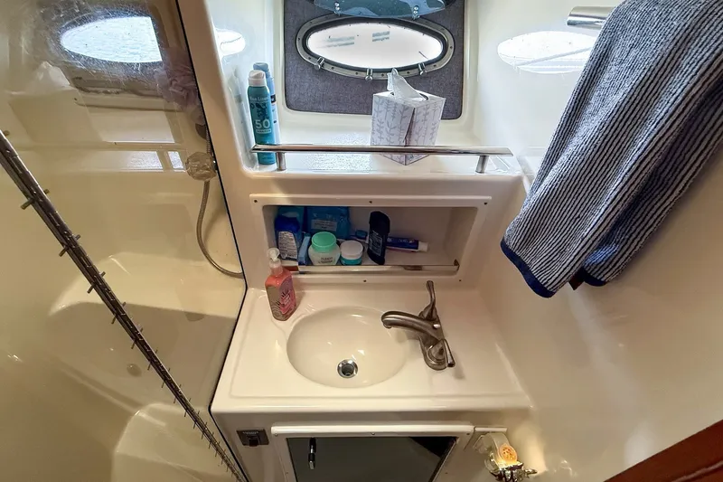 Slide: The Image of Bathroom sink area in a 1989 Tiara Yachts 3600 Convertible, featuring toiletries and a towel. - 42