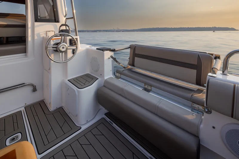 Slide: The Image of 2023 Cutwater C-30 Sedan boat interior with steering wheel and seating, overlooking calm waters. - 24