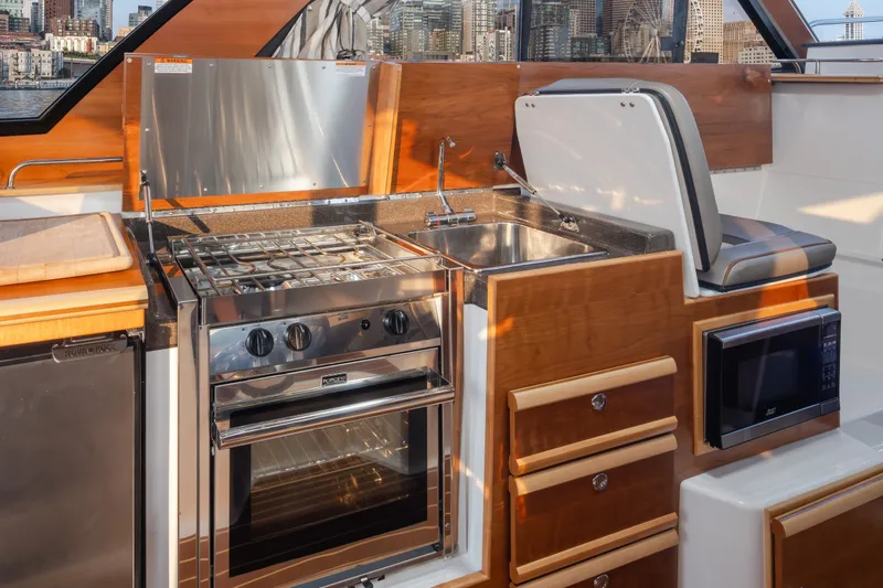 Slide: The Image of 2023 Cutwater C-30 Sedan kitchen with stove, sink, and microwave in a sleek design. - 32