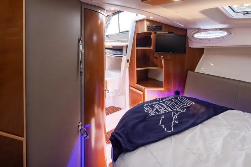 Slide: The Image of 2023 Cutwater C-30 Sedan interior cabin with bed, TV, and wooden storage shelves. - 36