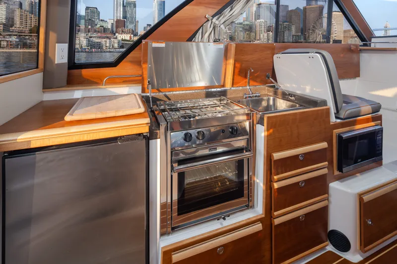 Slide: The Image of 2023 Cutwater C-30 Sedan yacht kitchen with stove, sink, and city skyline view. - 31