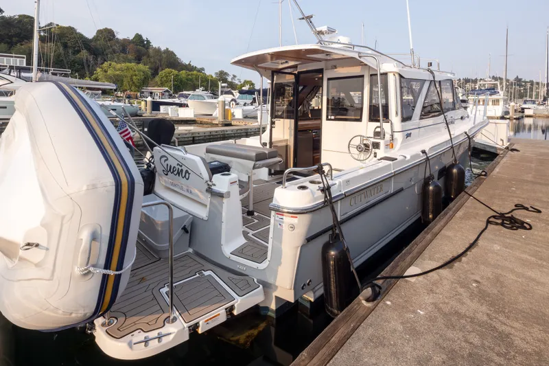 Slide: The Image of 2023 Cutwater C-30 Sedan docked at marina, featuring spacious deck and inflatable dinghy. - 49