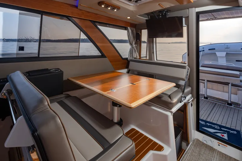 Slide: The Image of 2023 Cutwater C-30 Sedan interior with dining area, large windows, and scenic water view. - 28