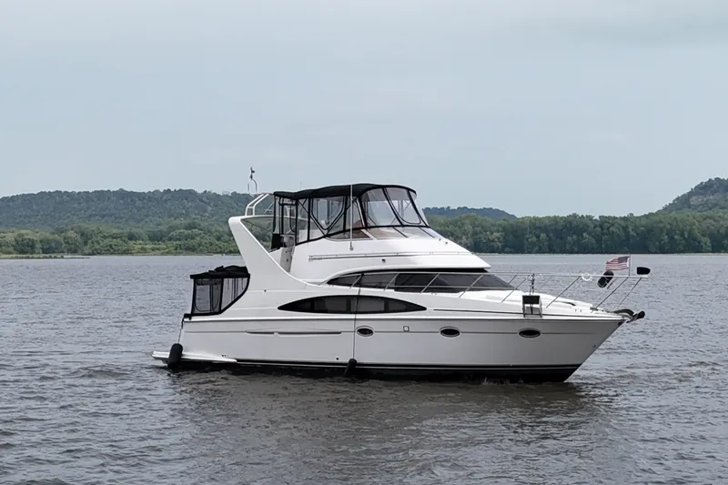 Slide: The Image of 2002 Carver 410 Sport Sedan yacht on a serene lake with forested hills. - 3