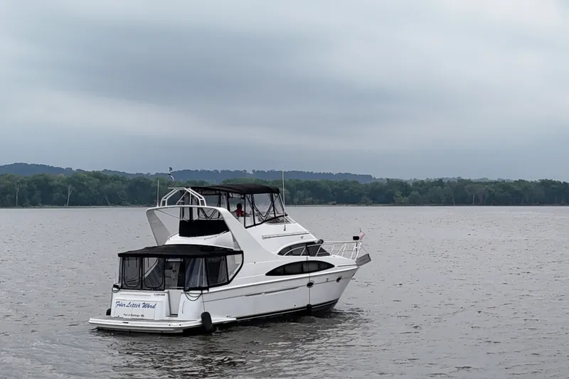 Slide: The Image of 2002 Carver 410 Sport Sedan yacht on a calm lake with forested shoreline. - 4