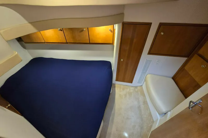 Slide: The Image of 2002 Carver 410 Sport Sedan cabin with blue bedding and wooden storage cabinets. - 13