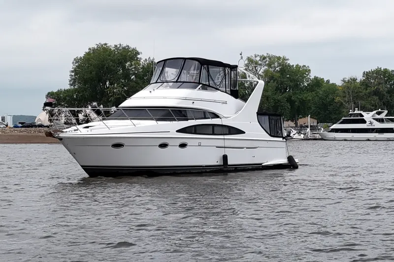 Slide: The Image of 2002 Carver 410 Sport Sedan yacht on calm water, surrounded by trees and other boats. - 2