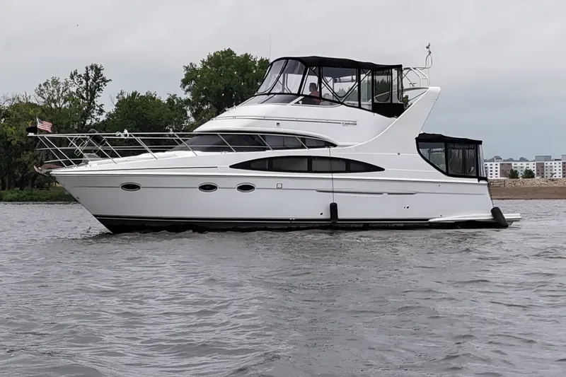 The Image of 2002 Carver 410 Sport Sedan yacht on water, side view with trees in background. - 1