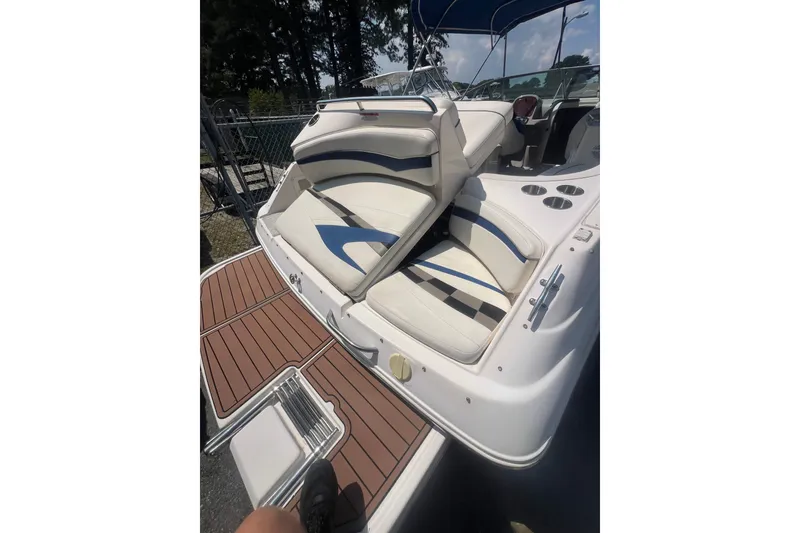 Slide: The Image of 2004 Rinker 282 Captiva Bowrider with white and blue seating, wooden deck, and cup holders. - 56